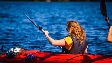 Una ragazza che pagaia in un kayak doppio durante una giornata estiva soleggiata.