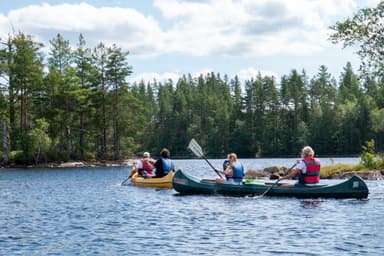 A group of people paddling in canoes, a joung girl is playing with a paddle.