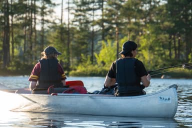 Two people in a canoe fishing in a calm lake.