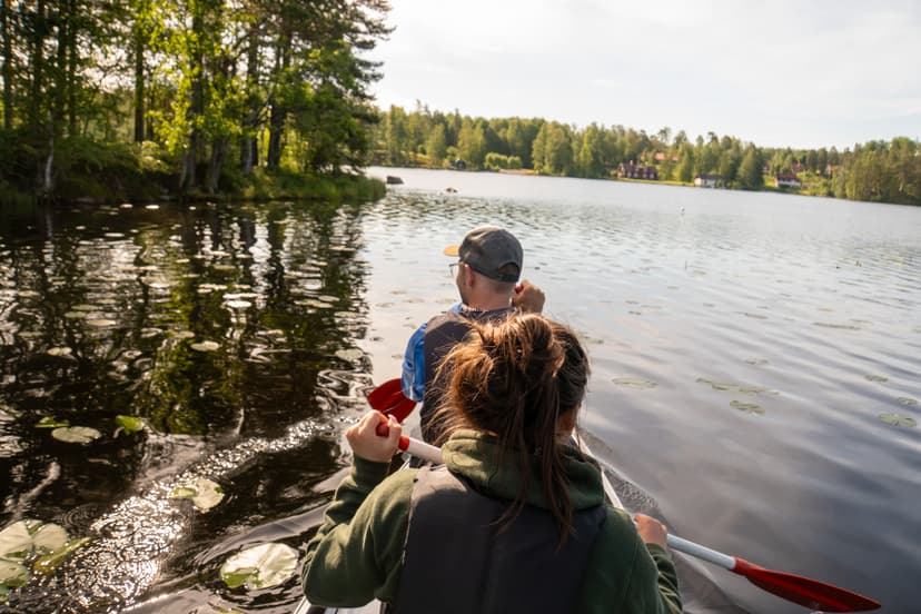 Deux personnes en canoë avec un petit village pittoresque au loin.