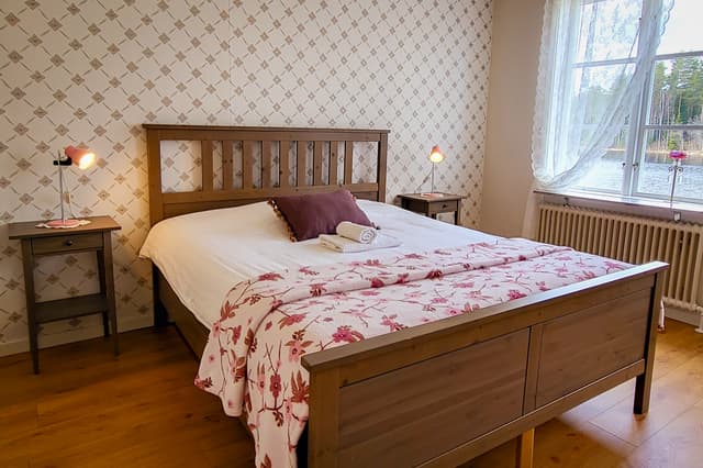 The canoeist apartment at River Lodge with a freshly made bed. The room is cozy and has a view of the lake and the forest.