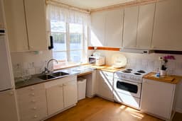 A more detailed view of the kitchen in the canoeist apartment at River Lodge. The kitchen is well-equipped and has a view of the lake.