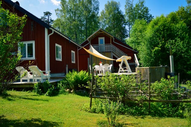 Trädgård med soltak, vedeldad badtunna och stolar för sittplatser.