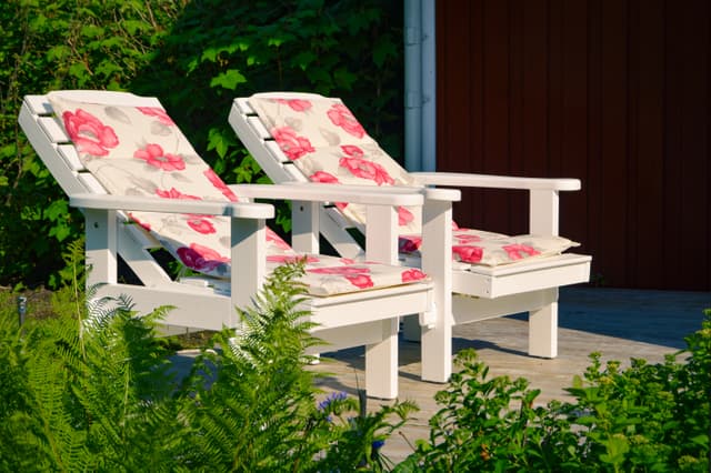 Två solstolar på verandan utanför vildmarksstugan i den svenska sommarsolen.