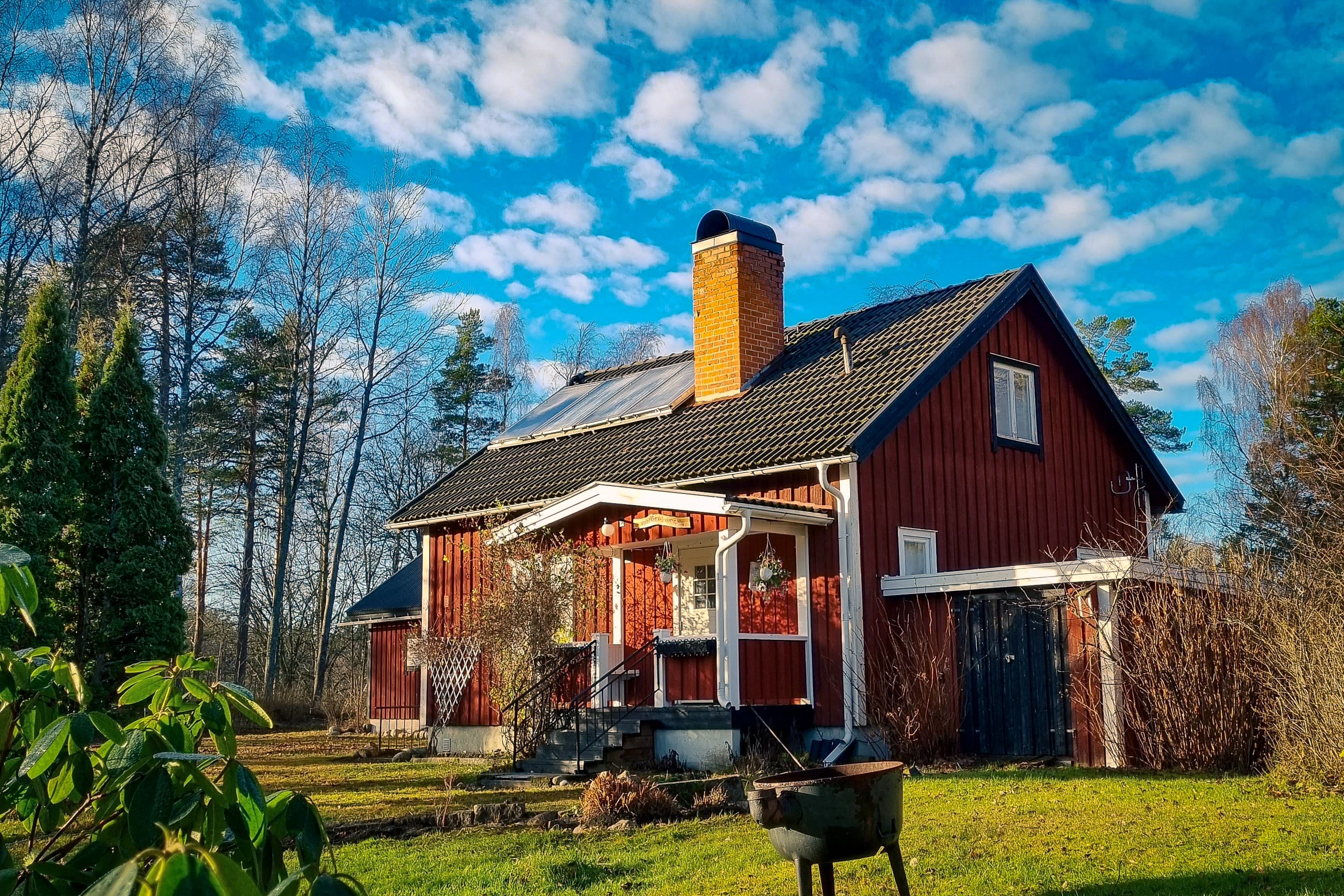 Framsidan av vildmarksstugan med små fluffiga moln på himlen.