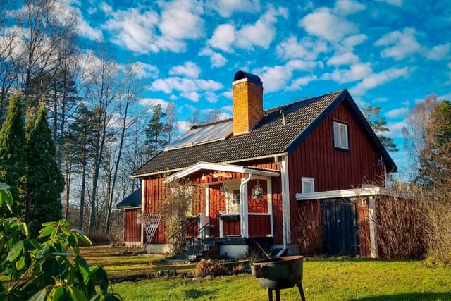 Framsidan av vildmarksstugan med små fluffiga moln på himlen.