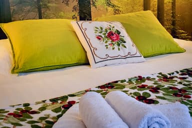 Cama con almohadas esponjosas y toallas en la cabaña en la naturaleza.