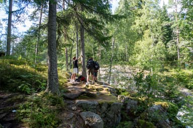 A family taking a break at Skräddartorpsfallet waterfall during a hiking tour in the Malingsbo-Kloten Nature Reserve in Sweden.