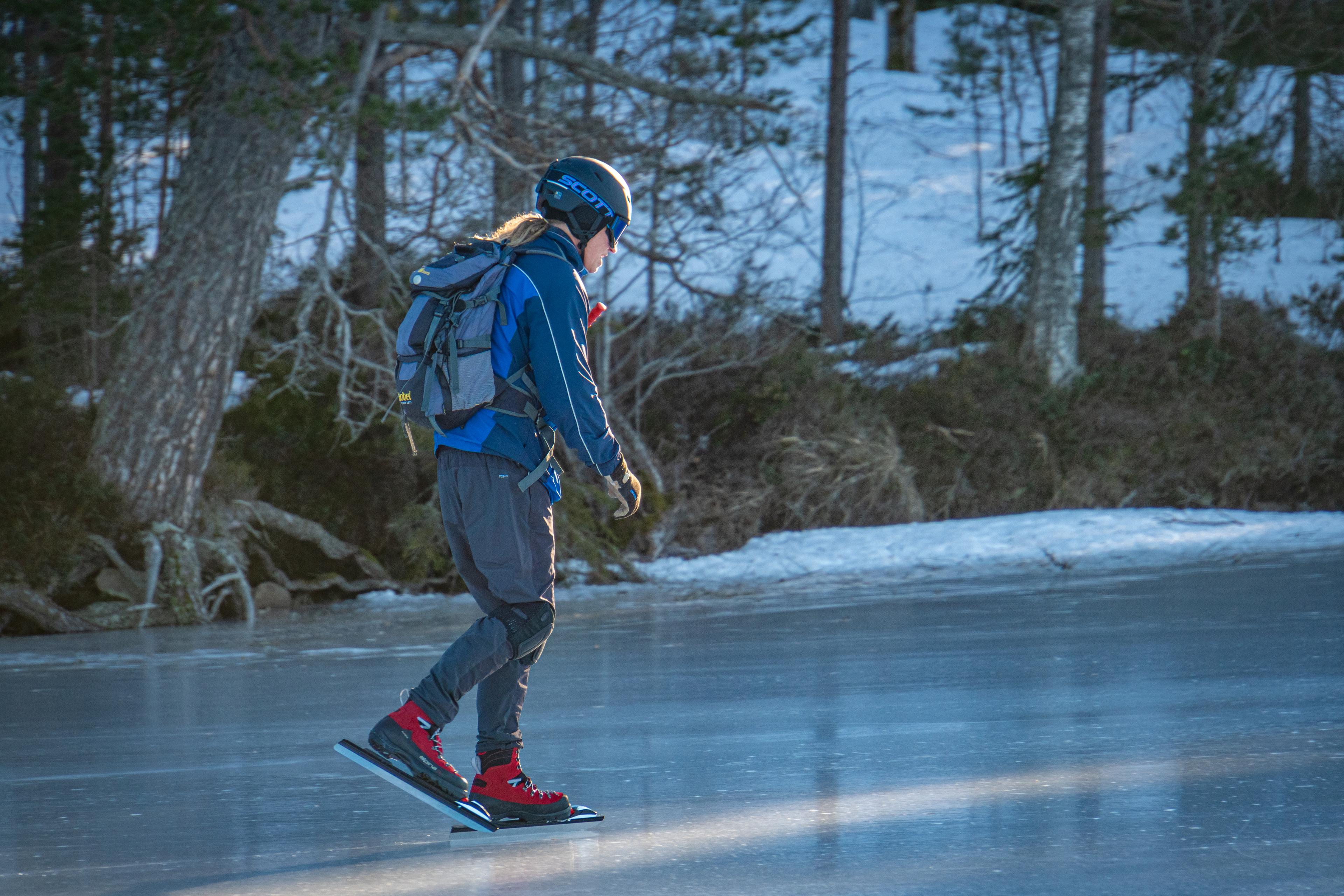 El guía de la excursión de patinaje sobre hielo Mikael Nilsson patina sobre un lago congelado con condiciones de hielo perfectas.