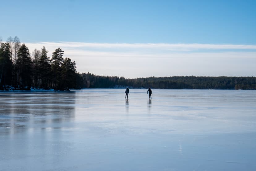 Ett skridskoåkarpar i fjärran njuter av klar himmel och slät is under en guidad skridskotur.