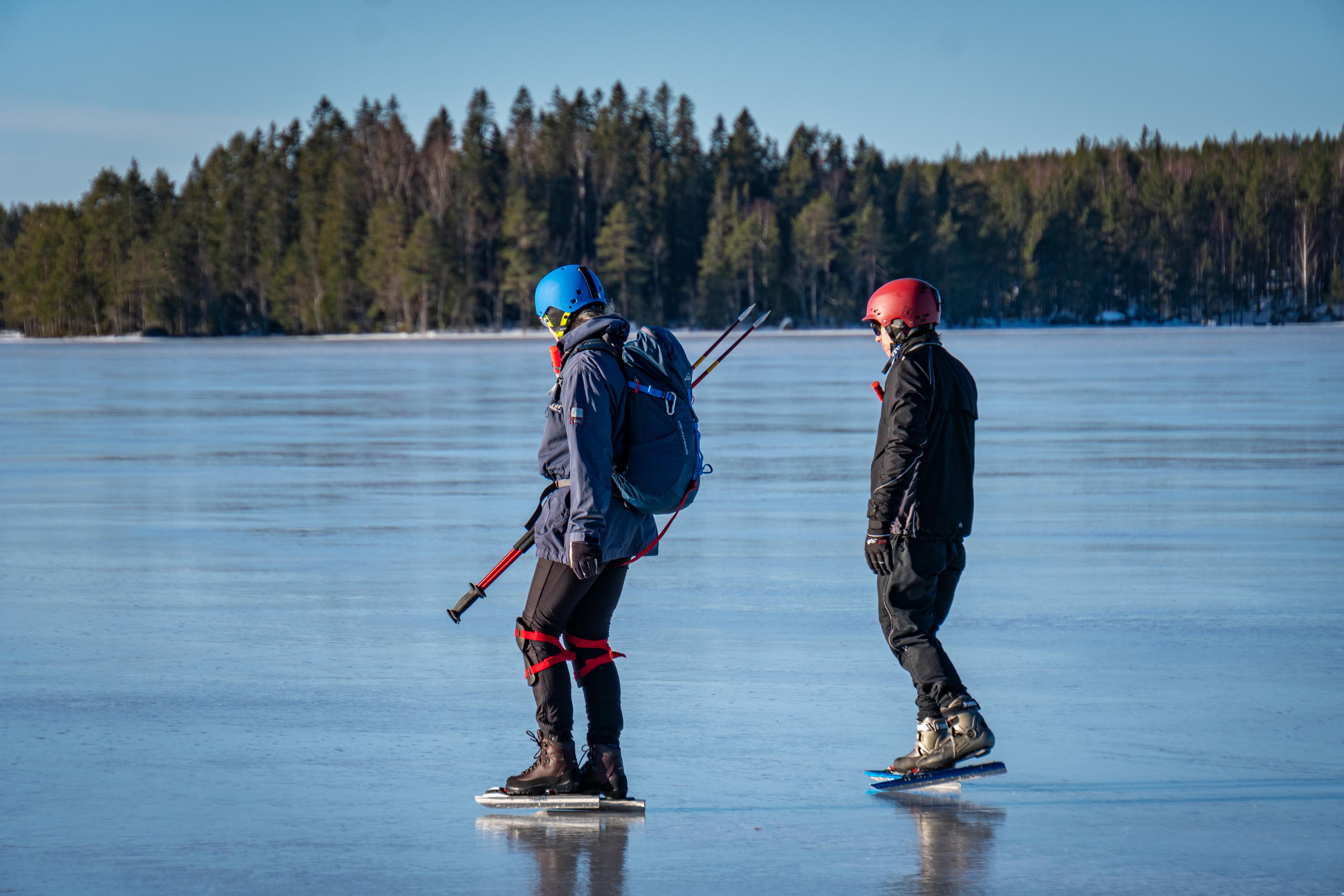 Un dúo de patinadores de cerca durante una excursión de patinaje sobre hielo guiada con cielo azul y hielo en el fondo.