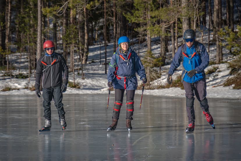Drei Eisläufer genießen eine Tour auf einem zugefrorenen See in der schwedischen Wildnis mit Nordic Discovery.