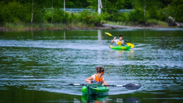 Kinderen kajakken in stille wateren en genieten van de natuur.