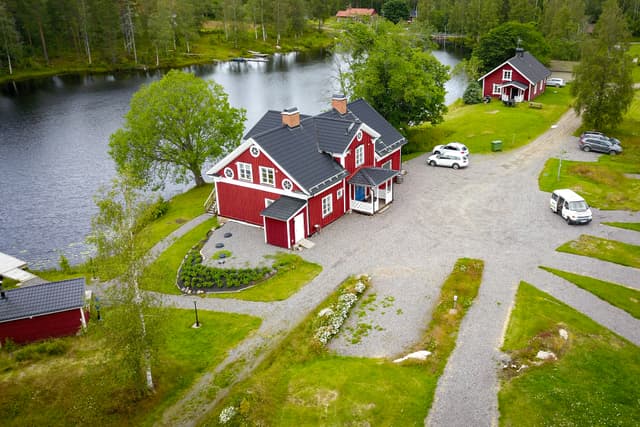 En överblick av River Lodge med sjön i bakgrunden och campingområdet i förgrunden. Bastun, simområdet och däcket syns ovanifrån.