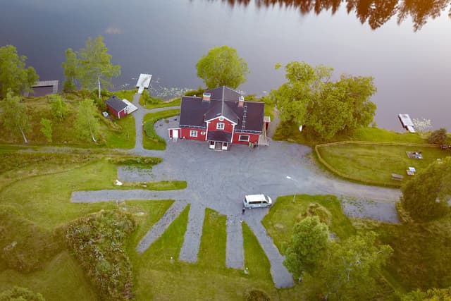 En överblick av flodstugan med bastu, badplats, däck och stor veranda.
