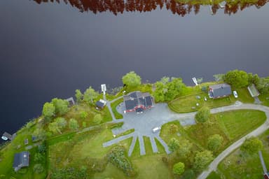 Luchtfoto van de River Camping. Het water is kalm en het campinggebied is omgeven door wildernis.