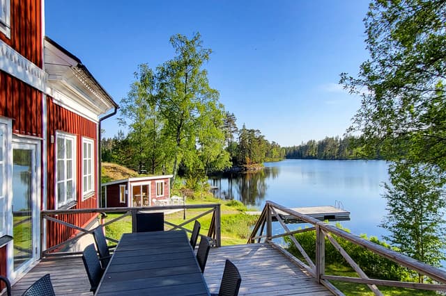 Den stora verandan på River Lodge med sittplatser för 12 personer omgiven av sjön och skogen.