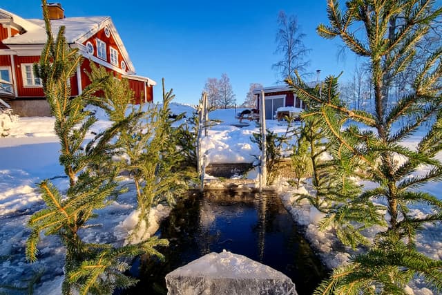 Ett hål i isen framför bastun på River Lodge. Bastun är varm och mysig en kall vinterdag.