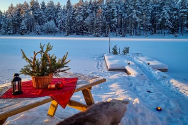 Nager dans l'eau glacée après une séance de sauna au River Lodge. Le banc a une peau de renne pour la chaleur, un chemin dans la neige mène au sauna.