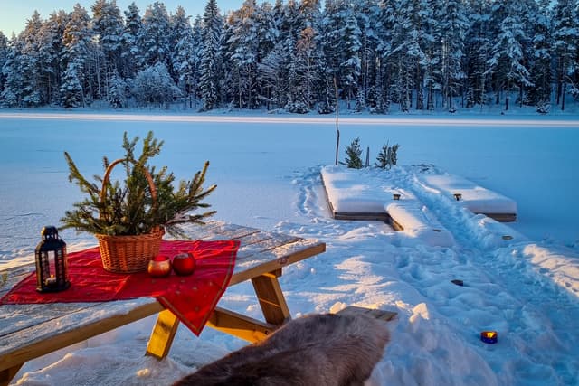 Simma i det iskalla vattnet efter en bastusession på River Lodge. Bänken har ett renhud för värme, en stig i snön leder till bastun.