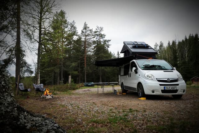 Een camper geparkeerd bij de wilderniscamping, met een warm vuur dat ervoor brandt.