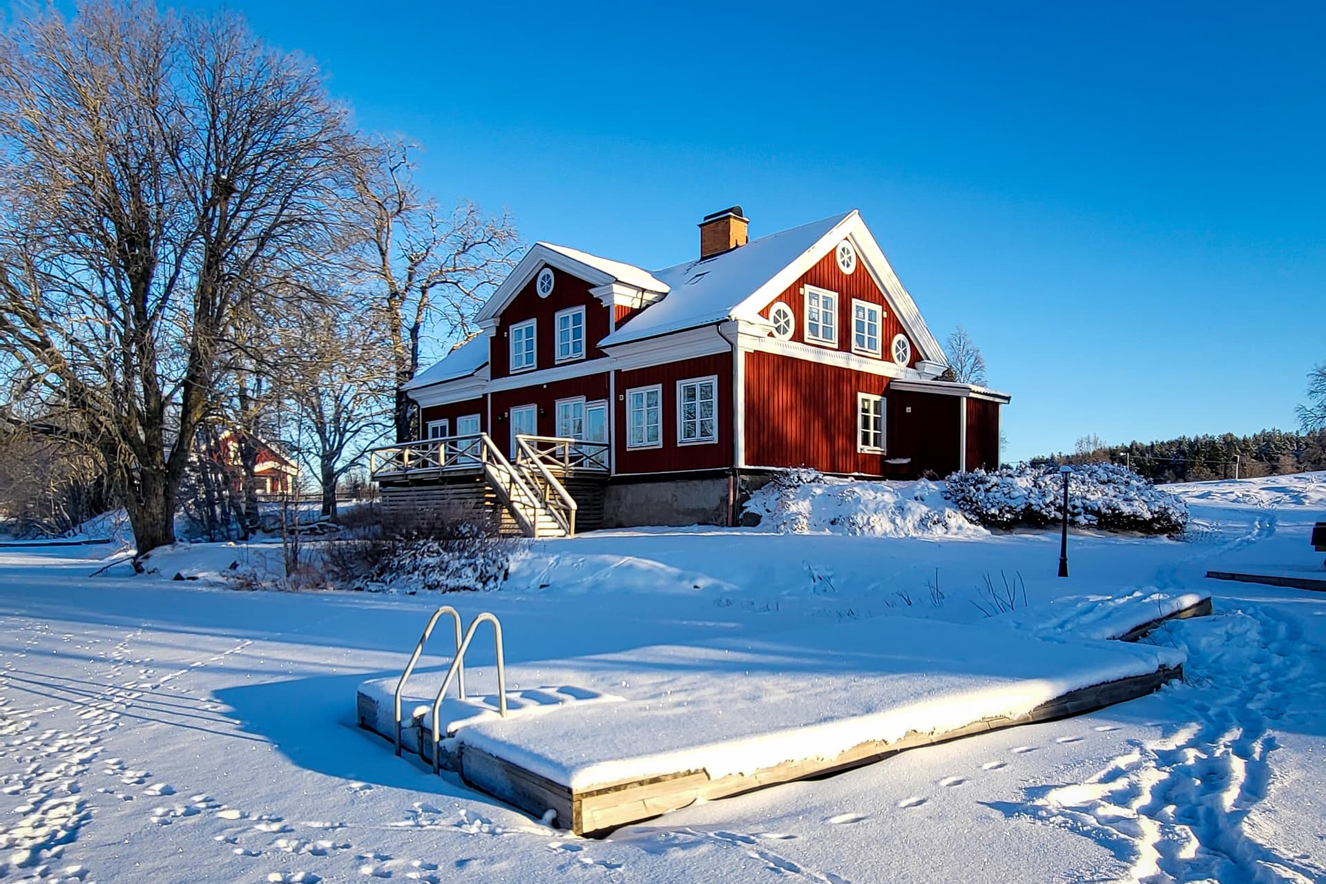 The deck at the River Lodge is covered in snow on a cold winter day. The snowy Swedish wilderness is visible in the background.