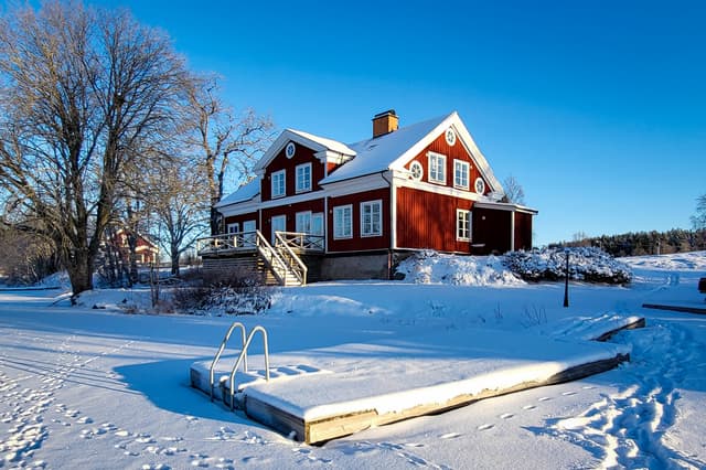 Bryggan vid River Lodge är täckt av snö en kall vinterdag. Den snöiga svenska vildmarken syns i bakgrunden.
